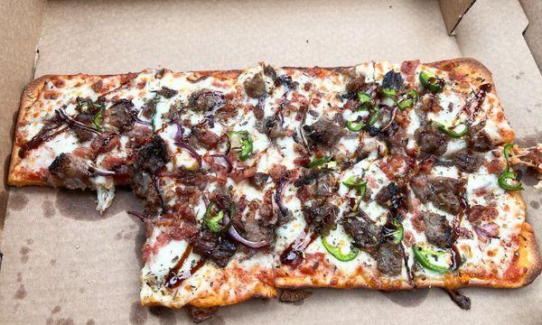 El Jefe flat bread pizza with brisket bar b que sauce jalapeños onions. Sorry I got hungry 1 piece was eaten in the car.