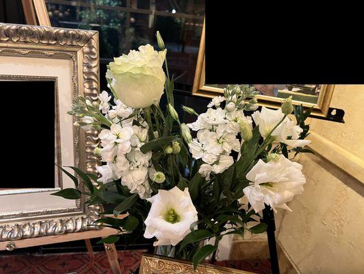 Flower arrangement on a round table and an easel with framed photographs