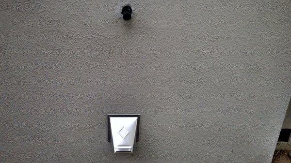 Hose from washing machines now drains water outside into a recycling tub (upper part of photo); vent for the dryer (lower pert of photo).