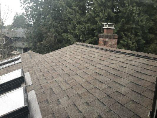 New roof with asphalt shingles, new ridge vent (right), and new flashing around skylights (left)