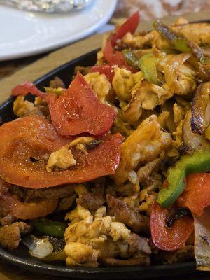 Close-up of The Fajitas Texanas main course. With shrimps, chicken, and steak, bell peppers, onions, and tomatoes.
