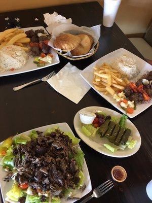 Beef shawarma salad, grape leaves appetizer, and two filet mug on kabob meals with basmati rice and fries, served with warm pita bread.