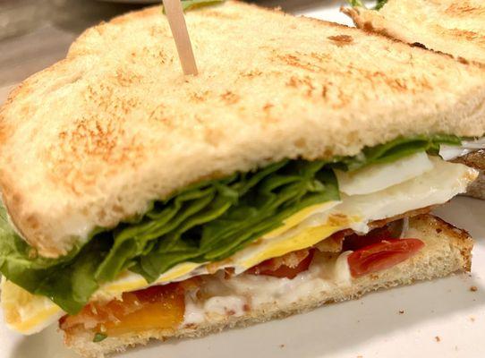 Absolutely fresh and delicious bacon, egg, spinach and tomato sandwich on Italian toast.