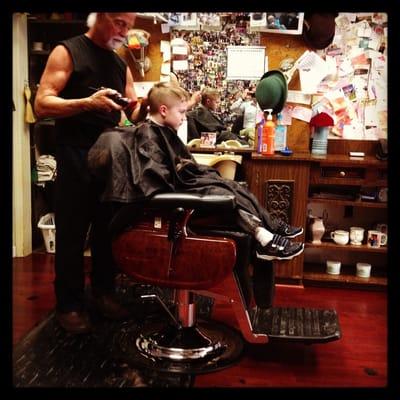 State Barber Shop with patron, barber, and photographer reflected in the mirror.
