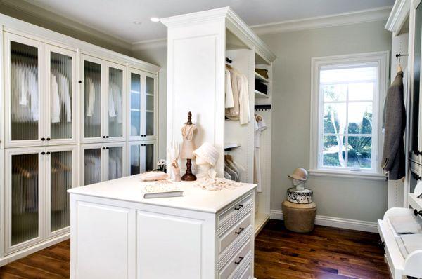 High-end Walk-in custom closet with glass doors and drawer island.