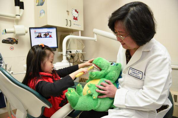 A CBWCHC dentist showing a child patient how to brush her teeth.