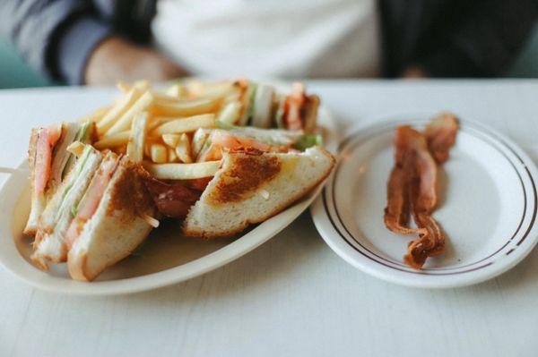 Club sandwich with fries and bacon on the side
