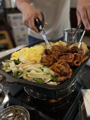 thinly sliced spicy pork belly heated over a burner + other sides on the metal tray