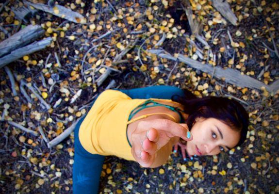 Side lunge while reaching up towards the sky on a yellow aspen leaf littered ground.