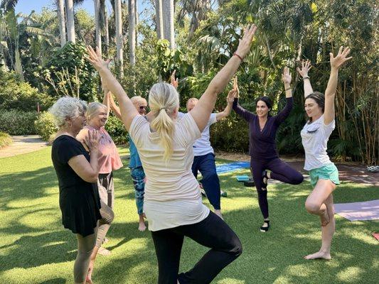 Instructor Vandana Dillon E-RYT200 (pictured center front) demonstrates Vrksasana (Tree pose) amongst the trees in Sunken Gardens.
