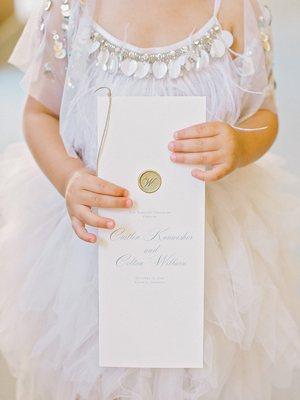 Wedding program with gold wax seal and romantic script font.