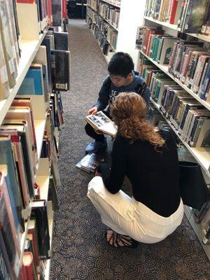Our lead Reading Club teacher helping students pick out books at the library.