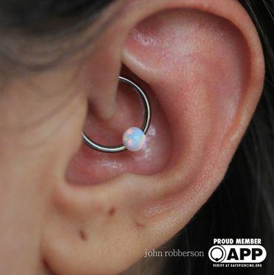Fresh daith piercing with a white opal captive bead ring. Piercing by John
