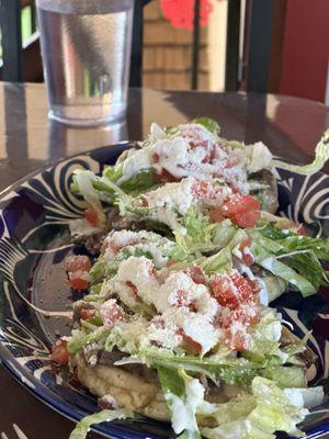 Carne asada sopes with lettuce, tomatoes, Mexican crema and cotija cheese.
