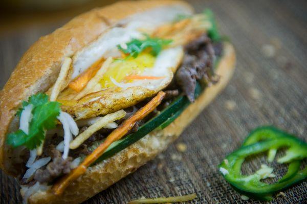 Seared Steak Banh mi with all the toppings and fried egg on top.