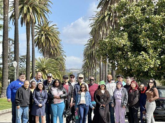 A large private group tour posing with palm trees and Hollywood sign during the tour with Legends Of Hollywood Tours