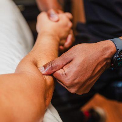 Applying deep tissue pressure to a client's forearm, targeting muscle tension and promoting relief through manual therapy.