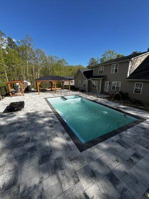 New Pool installed by Eco Landscaping Design team. This pool features 2 gazebos, a fire table, laminar fountains, and custom pavers, hot tub