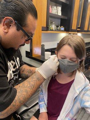 Piercer doing earlobe piercing