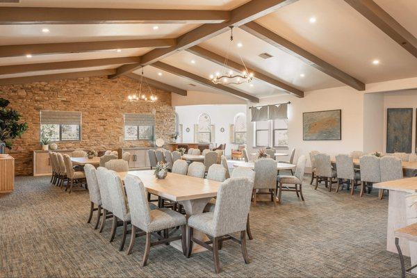 A room with tables and chairs and a stone wall