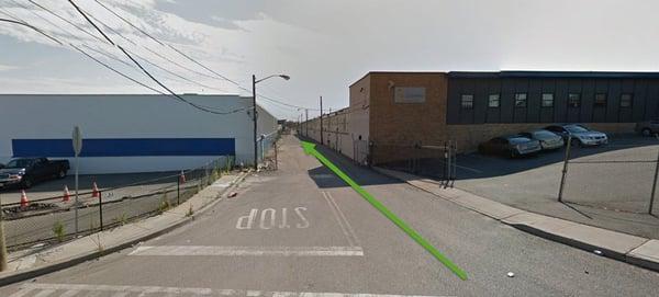 Follow the green arrow back between these two warehouses (please see my review for details).