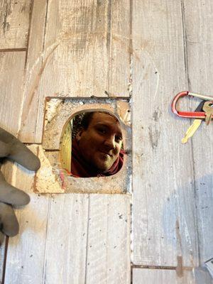 Kevin peeking through a toilet flange hole as he replaces the flange.