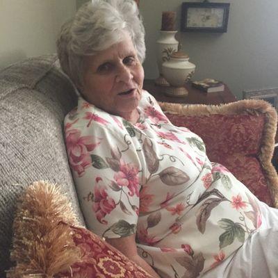 Sitting on her sofa in her apartment.