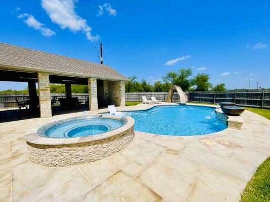 In-ground pool with a hot tub and slide.
