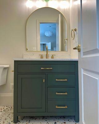 Bathroom cabinet with shaker-style doors, elegant green satin finish, and gold hardware for a timeless, sophisticated touch.