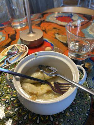 Pierogi served in a ceramic mini Dutch oven with iridescent artisanal cutlery.