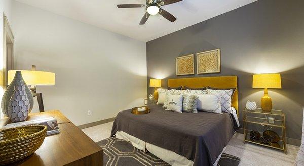 Modern bedroom at The Circuit Apartments in Houston features a stylish design with a plush upholstered headboard, warm accent...