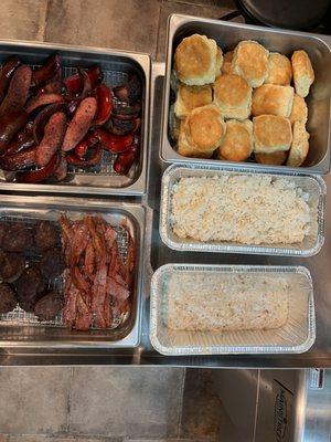 Breakfast selection of biscuits, rice, grits, hot links, bacon, turkey sausage, sausage patties, vegan sausage