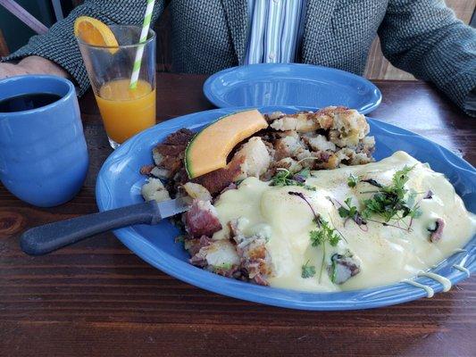 Corned beef eggs Benedict with a side of potatoes and freshly squeezed orange juice.