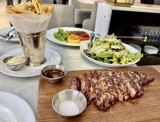 ribeye steak, truffle fries, Caesar salad, and salmon