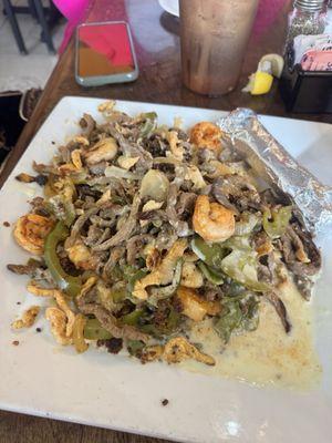 Nachos Chuy - steak, chicken, shrimp chorizo with onions, bell peppers and cheese over a bed of rice