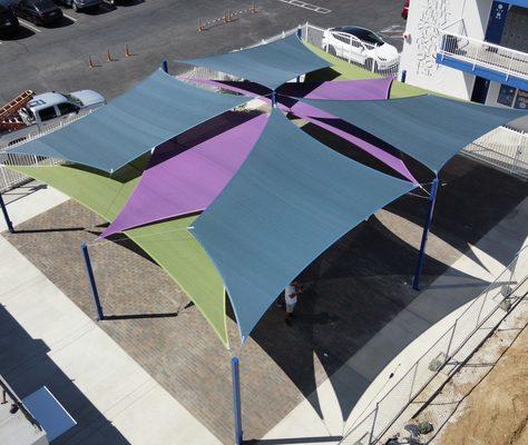 Large outdoor eating area covered with overlapping sail shades