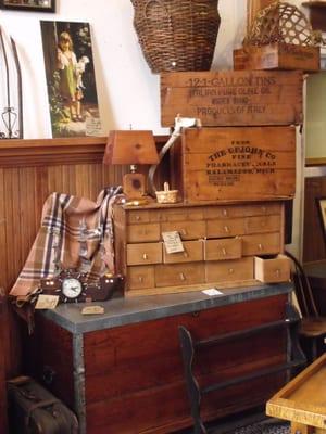 Advertising boxes stacked on multiple drawered pine cabinet.
