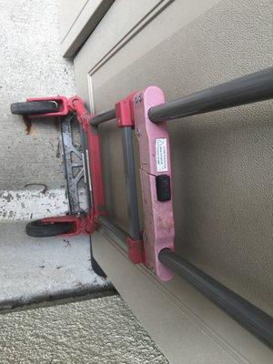 Broken hand truck pinned under heavy shed.