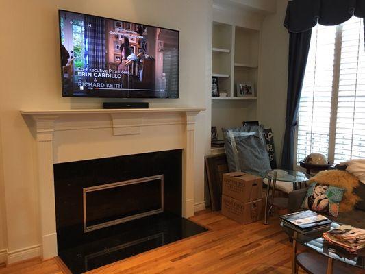 Wall mounted TV above fireplace and sound bar resting on mantle with concealed cables