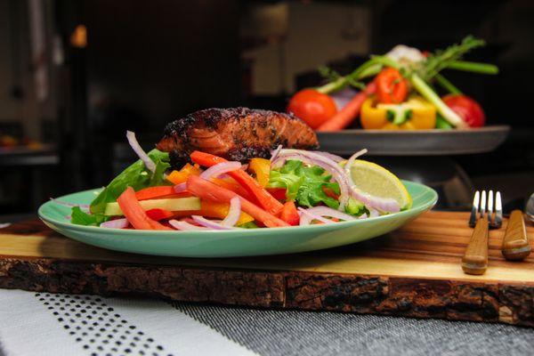 Seared Salmon on a bed of mixed greens and vegetables.