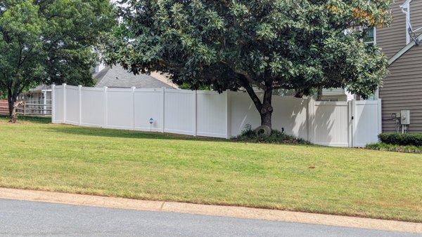 Fort Mill, South Carolina white vinyl privacy fence installed by our team to go around desired trees in yard and help contain family dog