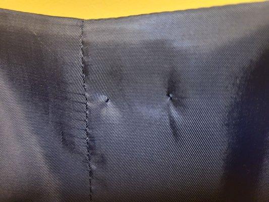 Holes left behind after a safety pin was carelessly stuck through a bespoke vest.