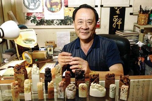Zong Chen Liu in his Chinatown shop displaying a few large intricately carved soap stone chops.