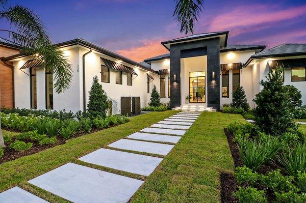 Entrance (concrete slabs, spaced out with grass between) leading to a new custom home.