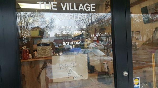 Front door with a "back in five minutes" sign