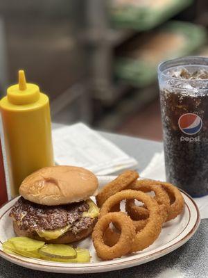Double cheeseburger with mustard, pickles, and onion rings with a root beer.