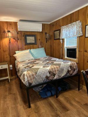 Crooked bed showing non functioning mini split and window AC unit.