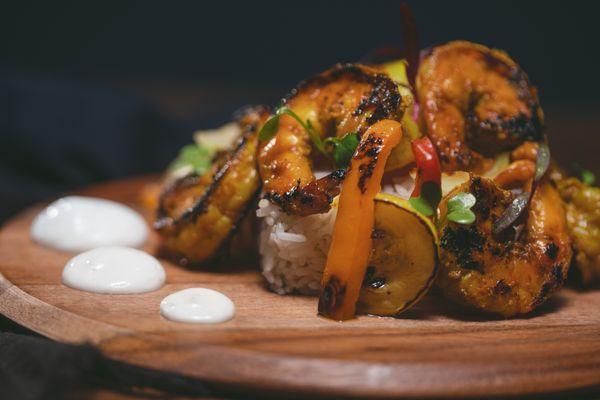 Shrimp Satay
Marinated, seared shrimp. Sautéed onions, bell peppers, squash. Cardamom scented Jasmine rice w/ Greek yogurt. chili oil.