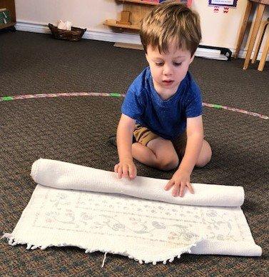Small hands...BIG work!  Rolling a floor mat takes concentration and dexterity!