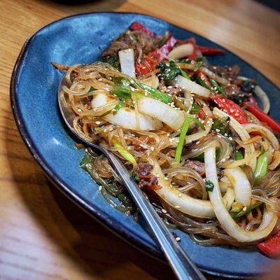 Japchae: Glass Noodles, Marinated Beef, Red Pepper, Carrots, Onions, Spinach, Mushrooms, Soy Garlic Sauce, Sesame Oil